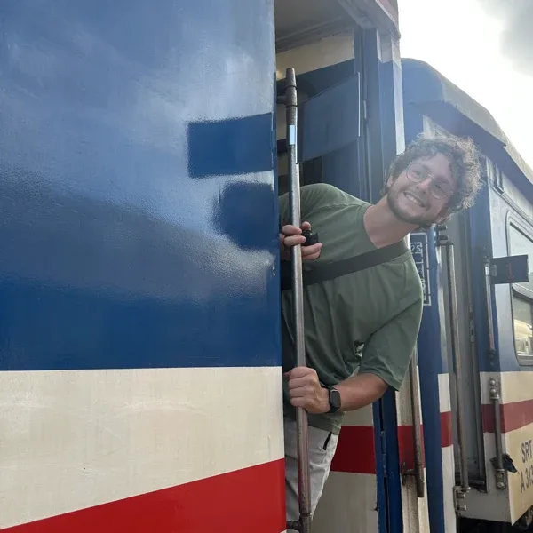 Quentin leaning out of a train door, smiling